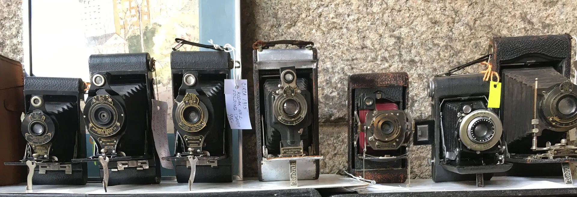 Three old cameras are on display in a room.